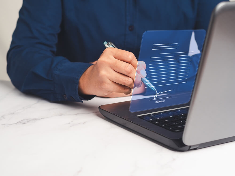 Homem com uma caneta na mão e um notebook a frente
